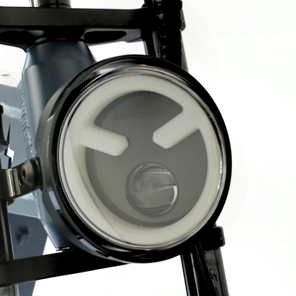 Close-up of an e-bike's front headlight, featuring a sleek circular design for enhanced visibility and safety during night riding.