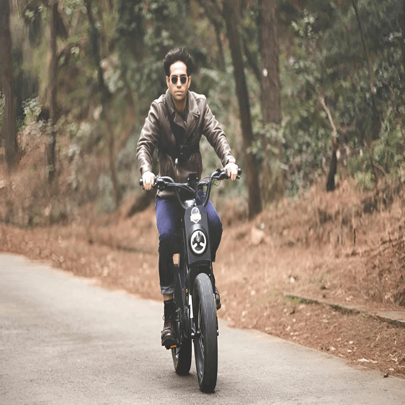  A man riding the EUNORAU e-bike on a forest path, illustrating the bike's off-road capabilities and rugged design.