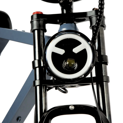 Front view of an e-bike's headlight with a sleek circular design, integrated into the suspension fork for enhanced visibility during night rides.