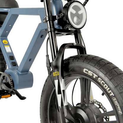 Close-up of an e-bike's front end, featuring a CST Scout tire, suspension fork, and integrated headlight, designed for stability and visibility on various terrains.