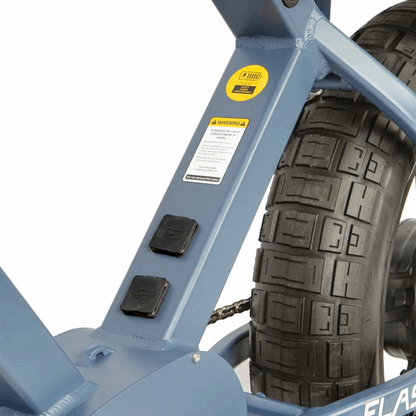 Close-up of an e-bike's frame with warning labels and rear CST Scout tire, emphasizing safety information and robust tire design.