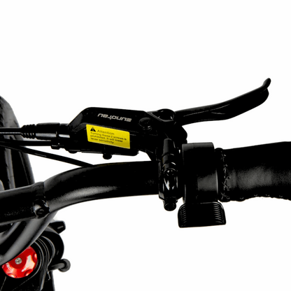 Close-up of an e-bike's handlebar showing the brake lever and caution label for safe and controlled braking.