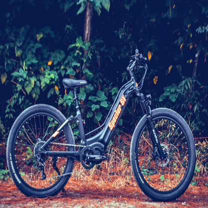 Side profile of the SPECTER-ST Full Suspension Mid-Drive Elite Electric Mountain Bike in a forested area, showcasing its rugged design and step-through frame.