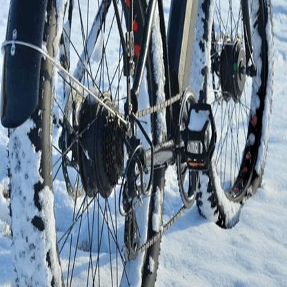 Side profile of the FAT-AWD Winter E-Bike covered in snow, emphasizing the bike's winter performance and rugged tires.