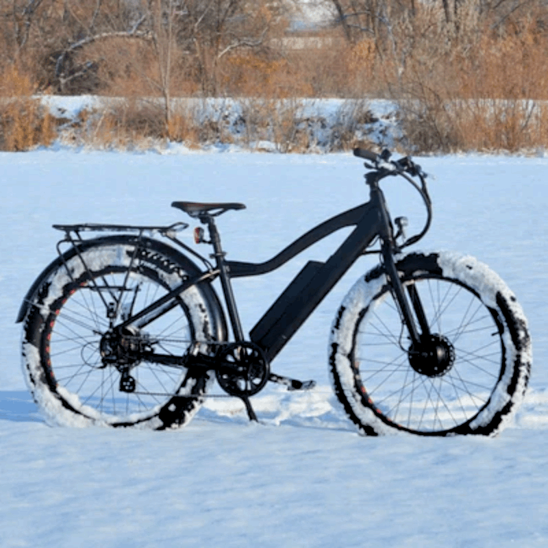 Electric bike with dual motors and fat tires, riding through snow, showcasing winter performance capabilities.